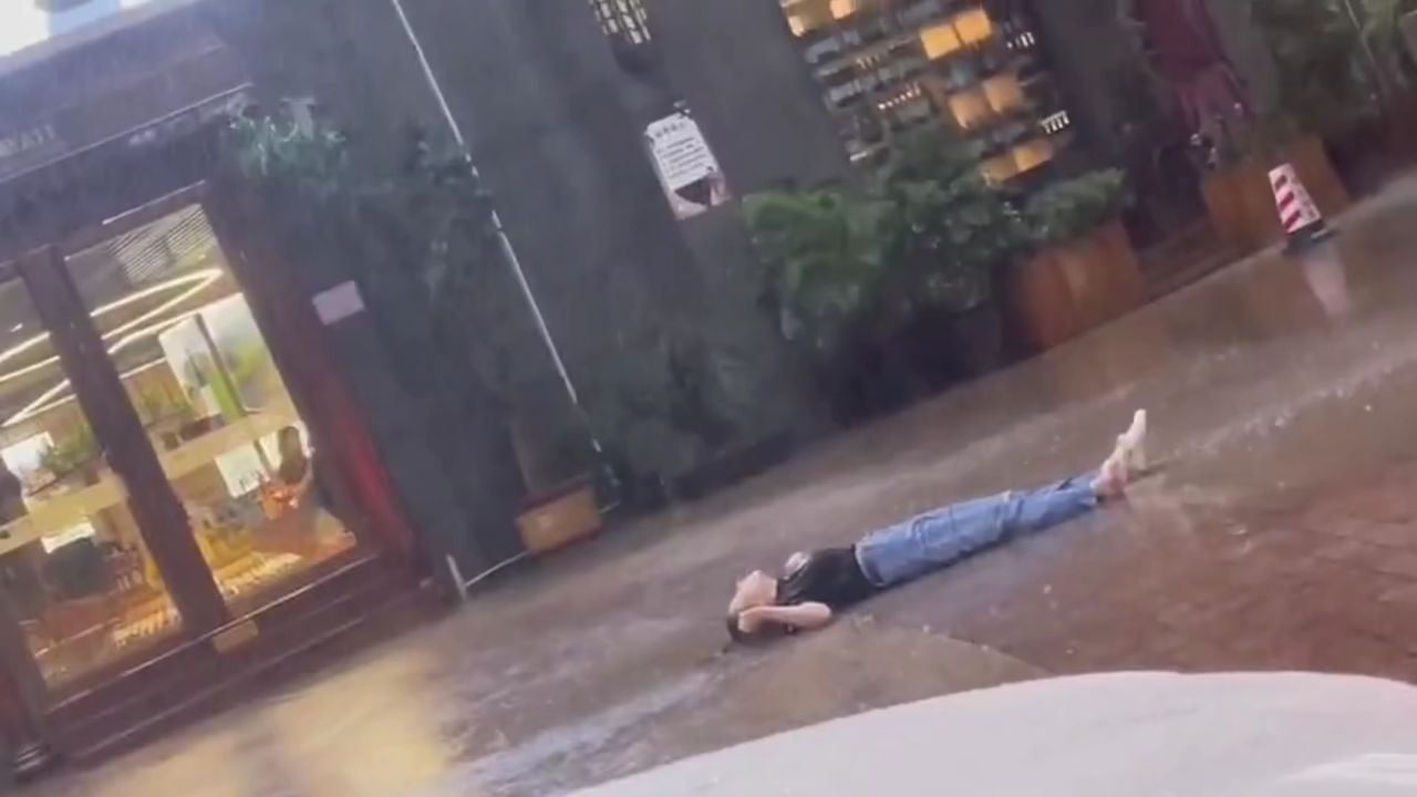 女子躺在大雨中淋雨,怎么劝都不听,好心人送上雨伞!