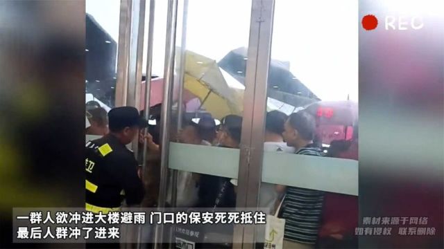 一群人欲冲进大楼避雨 门口的保安死死抵住大门 最后人群冲了进来